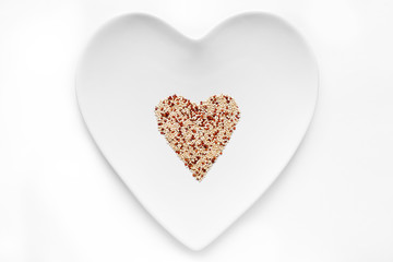 Quinoa grain lies in the shape of a heart on a white plate