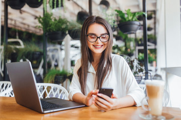 Young succesful brunette girl working in the office and drinking latte