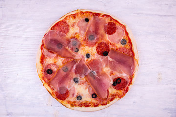 Pizza Carbonara with raw smoked bacon, salami and black olives