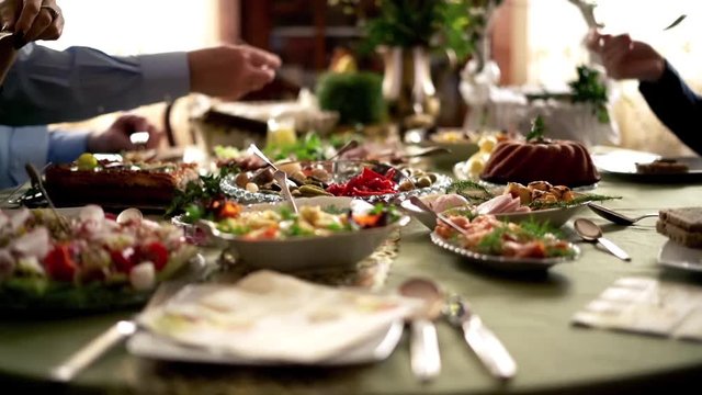 People around table during easter brekfast: focus on hands. 