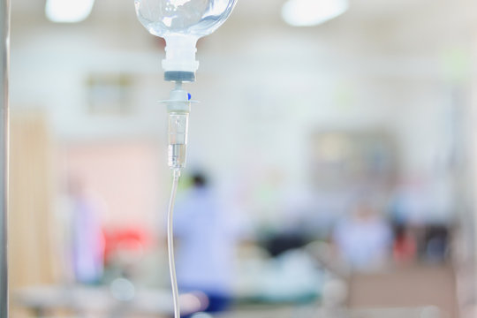 Medical saline iv drip close up with infusion pump in hospital, Saline intravenious on blurred doctor give medical and other attention to a sick person