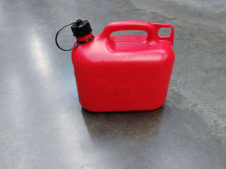 Red plastic gas for flammable liquids with a black lid on the concrete floor