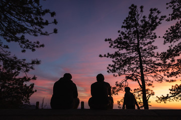 Friends spending time outdoors enjoying nature, watching the sun set. Vibrant colors in the sky 