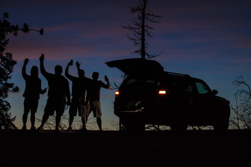 Silhouette of friends spending time outdoors enjoying nature, watching the sun set. Group photo