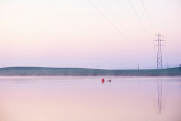 Fototapeta na wymiar Pylon pollution in countryside landscape telephone cable line at sunset at boat lake