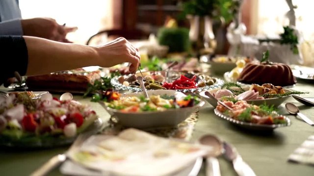 People around table during easter brekfast: focus on hands. 