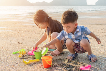 Cute little Asian children playing on sea beach in Summer in thailand.
