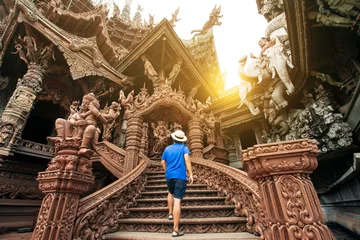 Foto op Canvas A man tourist is sightseeing inside the Ancient wooden Sanctuary of Truth in Pattaya, Thailand. © BUSARA