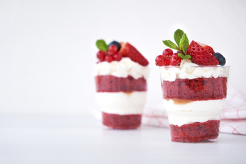Trifle red velvet. Cake layered dessert in glass with fresh berry, mint leaves.
