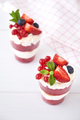 Trifle red velvet. Cake layered dessert in glass with fresh berry, mint leaves.