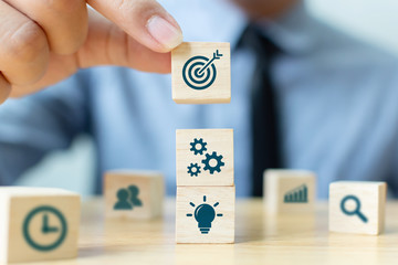 Concept of business strategy and action plan. Businessman hand putting wood cube block on top with icon