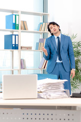 Young handsome male employee with too much work in the office  