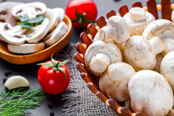 Fresh sliced champignon in wooden spoon. Cooking homemade dishes of white ripe mushroom with parsley, dill and tomatoes cherry