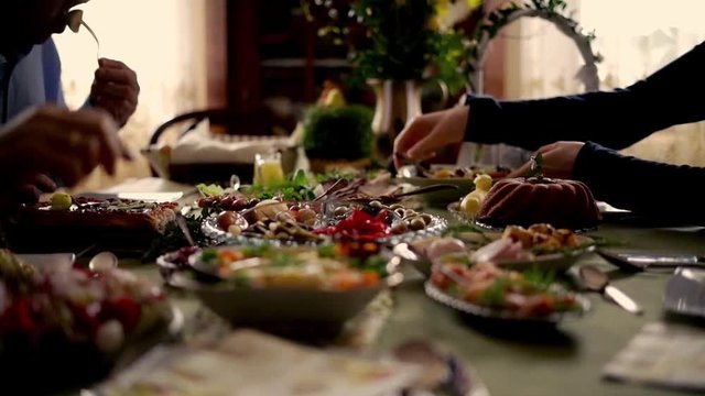 People around table during easter brekfast: focus on hands. 