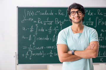 Young male student mathematician in front of chalkboard 