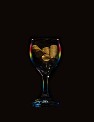 Wne glass filled with corks on a black background