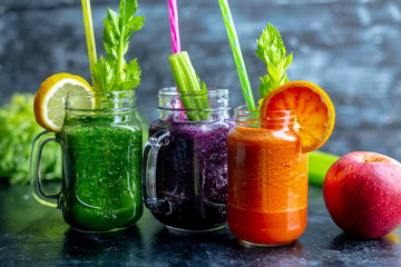 vegetable and fruit smoothies in various colors on a dark, warm background
