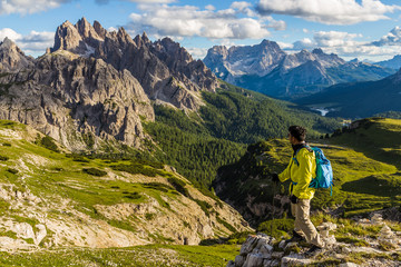 Male asian hiker looking at majestic view of Dolomites moutain range in Tre Cime di Lavaredo trail - obrazy, fototapety, plakaty