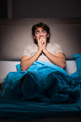 Young man scared in his bed having nightmares