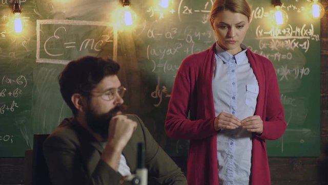 Student communicates with the teacher at the board. Classmate Educate Friend Knowledge Lesson Concept. Teacher is sitting at the table in classroom. Final exam test in university, Back to school.