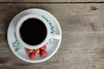 Hot coffee vintage cup with fresh organic red coffee beans on the wooden table