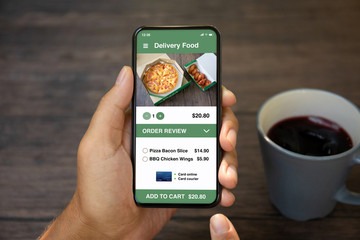 Male hands holding phone with app delivery food on screen