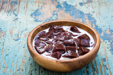 Slices of raw beef liver soaked in milk in a wooden bowl on the table