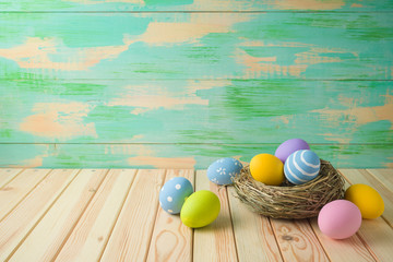 Easter holiday background with easter eggs in bird nest on wooden table