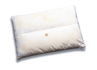 Old pillow with yellow stains isolated on white background