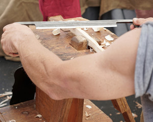 Crafts person carving wood with blade