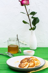 Ready-to-eat sweet cottage cheese pancakes with honey on a plate on a wooden table