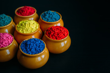 Colorful Holi powder in cups closeup. Bright colours for Indian holi festival in clay pots....