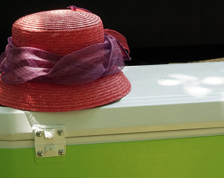 Red Sun Hat On Top Of A Vintage Cooler