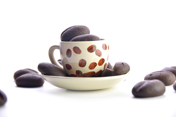 chocolate coffee beans in a mug on a saucer, white background