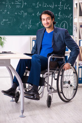 Young handsome man in wheelchair in front of chalkboard 