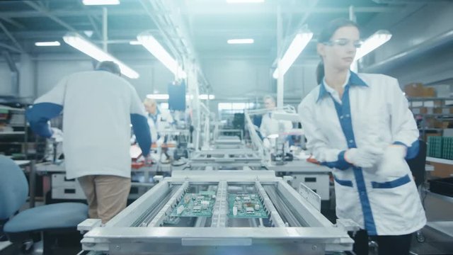 Time Lapse of Electronics Factory Workers Assembling Circuit Boards by Hand While it Moves on the Assembly Line. High Tech Factory Facility.
