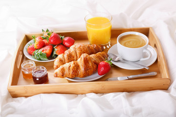 breakfast tray in bed : coffee, croissants, juice and fresh strawberries