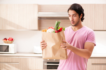 Young handsome man with vegetables in the kitchen 