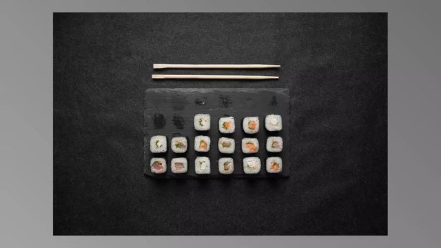 Sushi timelapse. rolls, maki, nigiri on black stone slate on dark background copy space