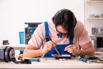 Young male contractor repairing computer  