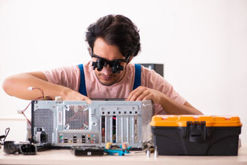 Young male contractor repairing computer  