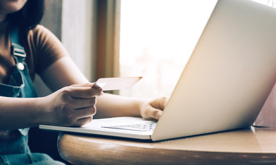 Close up woman hand holding credit card and typing keyboard laptop about shopping online concept.