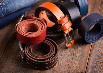 Leather colored belts on a wooden table.