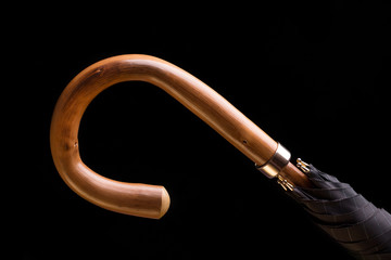 The handle of the umbrella canes on a black background. Umbrella with a wooden handle. 