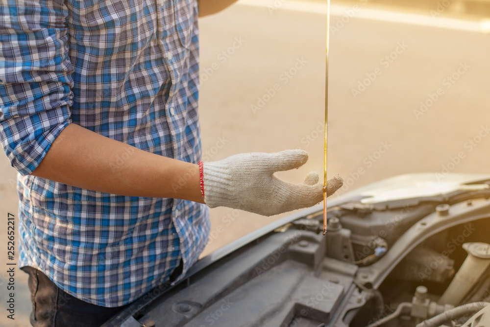 Poster mechanic hand checking oil level ,driver on the road having problem with a car. man checks the oil l