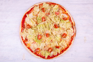 Pizza Caesar, is served with lettuce leaves and chicken breast in sauce