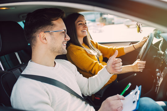 Driving School Or Test. Beautiful Young Pregnant Woman Learning How To Drive Car Together With Her Instructor.