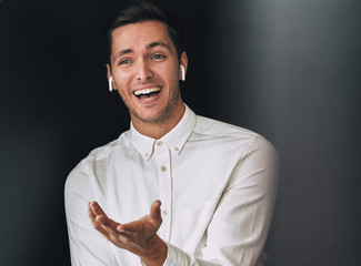 Cheerful young handsome man have a conversation with colleagues during meeting, posing over black...