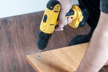 is the process of assembling furniture from chipboard. in the hands of a rechargeable screwdriver...