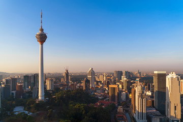 Fototapeta premium Menara Kuala Lumpur Tower with sunset sky. Aerial view of Kuala Lumpur Downtown, Malaysia. Financial district and business centers in urban city in Asia. Skyscraper and high-rise buildings at noon.